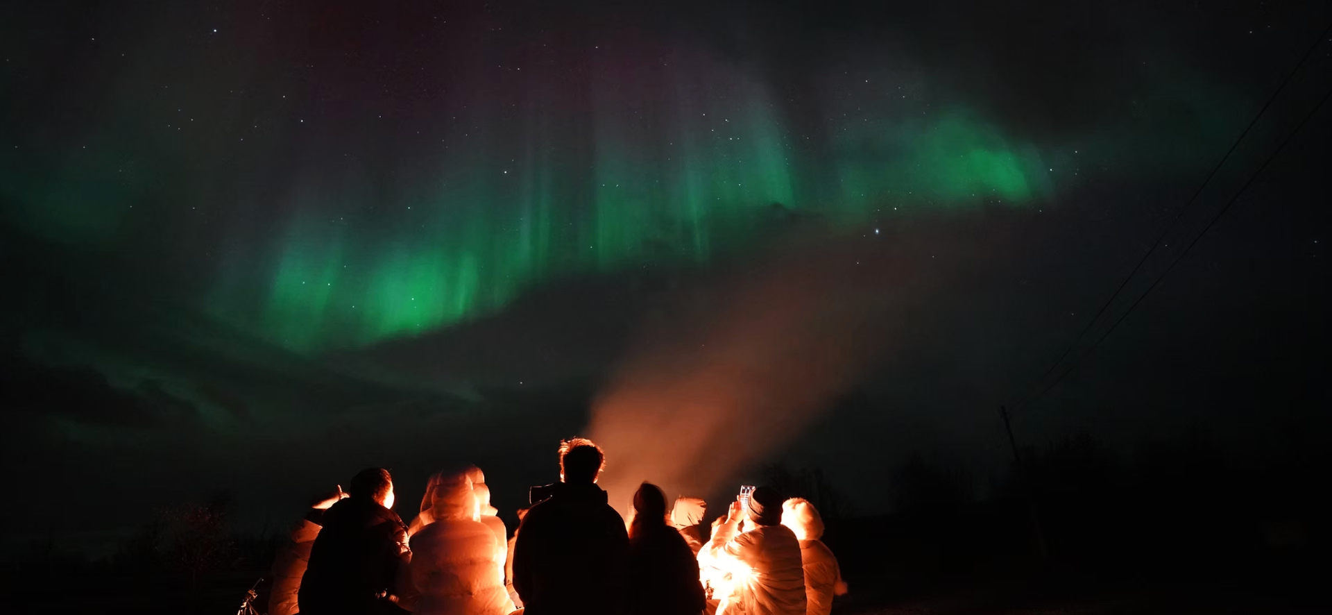 A warm Arctic cabin and bonfire under the night sky